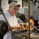 A male employee operates a piece of manufacturing equipment at Cogsdill in the Central SC Region