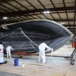 A few employees work on the hull of a ship at Victory Boats in the Central SC Region