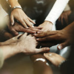 Diverse group of people with hands in a circle, teamwork